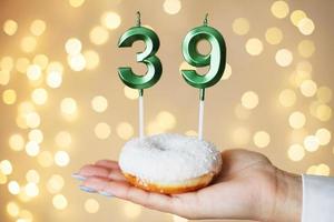 mujer sosteniendo un pastel con las velas número 39 en un fondo bokeh borroso festivo foto