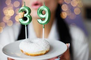 mujer sosteniendo un pastel con las velas número 39 en un fondo bokeh borroso festivo foto