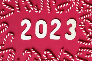 Christmas composition with candy canes and number 2023 on a red background. Copy space for text photo