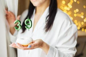 woman holding a cake with the number 39 candles on festive blurred bokeh background photo