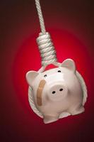 Piggy Bank with Bandage Hanging in Hangman's Noose on Red photo