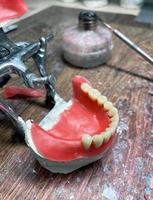 Artificial dentures in the manufacturing steps in the dental lab. Dental orthodontic mold with tools. Natural full prosthesis made of quality materials in plaster model. Selective focus, close up photo