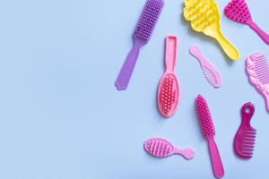 Hair care is a creative concept. Colored doll combs on a blue background. Copy space photo