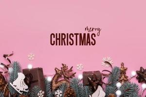 Merry Christmas text. Greeting card with winter holidays decoration top view, flat lay on pink background photo