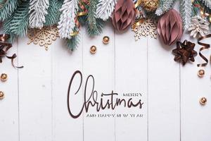 Christmas background with flat lay snow pine trees, paper and wooden Christmas toys on wooden background photo