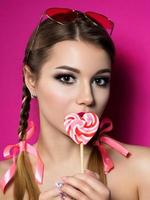 Young beautiful woman holds heart shaped lollipop