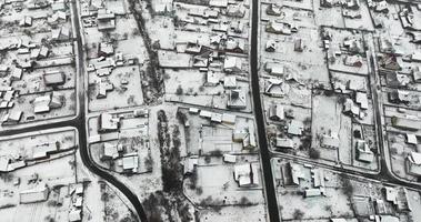 vuelo sobre la vista panorámica aérea de invierno del pueblo con casas, graneros y camino de ripio con nieve