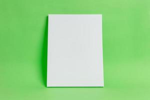 White art canvas on green surface. Clean, blank surface for mockup, art presentation. Art template photo