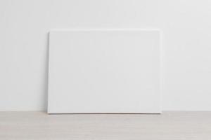 Art canvas in a horizontal position on the floor leaning against a white wall. Clean cloth for mockup art presentation photo