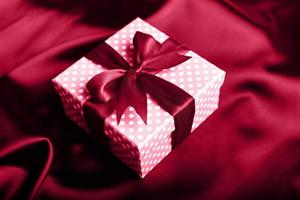 Magenta gift box with a bow on a magenta background. Holiday greeting card. photo