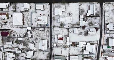 volo al di sopra di aereo panoramico inverno Visualizza di villaggio con case, fienili e ghiaia strada con neve video
