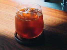 Ice black coffee in a cup on wooden table and Coffee shop blur background with old wood grain image photo