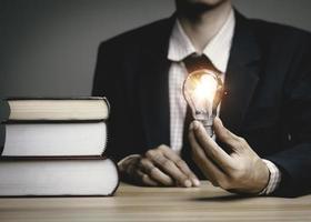 Businessman holding a light bulb think problem solving. business competition planning teamwork,International book, ideas and competition and strategy, business success concept,strategic concept. photo