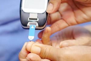 el médico usa guantes con lanceta en el dedo para controlar el nivel de azúcar en la sangre con un medidor de glucosa. foto