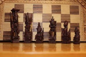 Mayan chess pieces photographed on a background showing a chess board photo