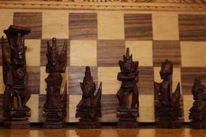 Mayan chess pieces photographed on a background showing a chess board photo