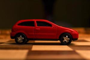 Red vehicle toy on a chessboard with various unique patterns drawn on it photo