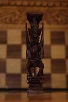 Mayan chess pieces photographed on a background showing a chess board photo