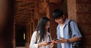 retrato de feliz pareja asiática verifica la ubicación en el mapa en línea del teléfono inteligente en el antiguo templo. hombres y mujeres sonrientes usando la aplicación de mapas de navegación de teléfonos móviles. concepto de vacaciones, viajes y pasatiempos. video