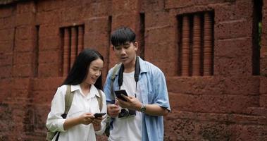 feliz pareja asiática selfie en smartphone en templo antiguo. mujer joven con teléfono móvil. hombre y mujer sonriendo y mirando el celular. concepto de vacaciones, viajes y pasatiempos. video