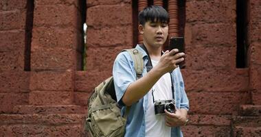 un homme asiatique préoccupé vérifie l'emplacement sur la carte en ligne du smartphone. un jeune homme déconcerté à la recherche de la bonne façon de se perdre dans un temple antique à l'aide d'une application de carte de navigation pour téléphone portable. notion de vacances. video