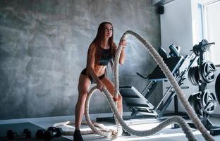 Young fitness woman with slim type of body doing exercises with knots in hands photo