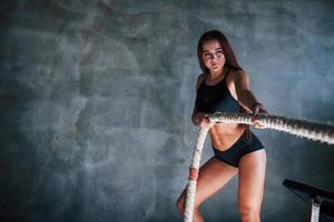 Young fitness woman with slim type of body doing exercises with knots in hands photo