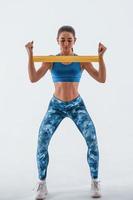 With yellow resistance band. Young woman with slim body type isolated against white background photo