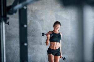 mujer joven fitness está en el gimnasio con pesas en las manos foto