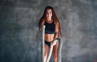 una joven deportista con un tipo de cuerpo delgado y ropa deportiva negra está en el gimnasio foto