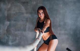 Young fitness woman with slim type of body and in black sportive clothes is in the gym photo