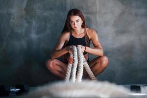 Young fitness woman with slim type of body sits with knots in hands photo