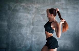 Young fitness woman with slim type of body and in black sportive clothes is in the gym photo