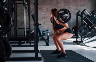 Young fitness woman with slim type of body doing exercises by using barbell photo