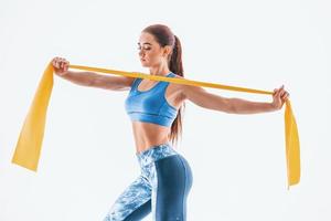 With yellow resistance band. Young woman with slim body type isolated against white background photo