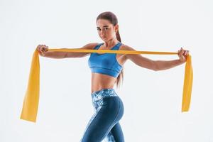 With yellow resistance band. Young woman with slim body type isolated against white background photo