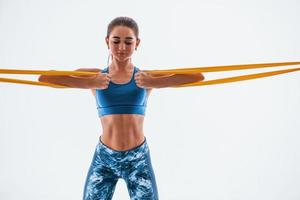 With yellow resistance band. Young woman with slim body type isolated against white background photo