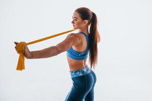 With yellow resistance band. Young woman with slim body type isolated against white background photo