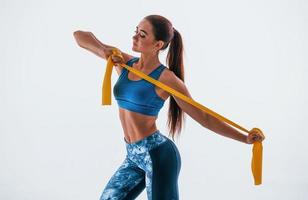 With yellow resistance band. Young woman with slim body type isolated against white background photo