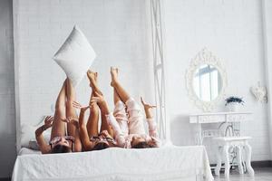 Playing with pillows. Happy female friends having good time at pajama party in the bedroom photo