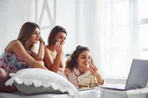 viendo películas en la computadora portátil y comiendo palomitas de maíz. amigas felices pasando un buen rato en la fiesta de pijamas en el dormitorio foto