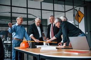 Aged team of elderly businessman architects works with plan in the office photo