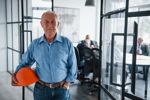 Portrait of senior man that stands in front of aged team of elderly businessman architects that have a meeting in the office photo