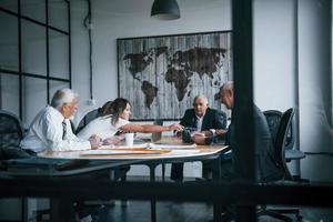 Aged team of elderly businessman architects have a meeting in the office and works with young woman photo