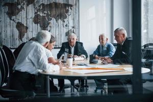 Aged team of elderly businessman architects have a meeting in the office and works with young woman photo