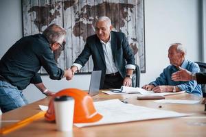 Doing handshake. Aged team of elderly businessman architects have a meeting in the office photo