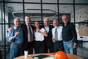 un equipo anciano de arquitectos de hombres de negocios de edad avanzada se encuentra en la oficina junto con una niña foto