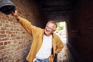 Stylish senior in fashionable clothes and in glasses relaxing in the city photo