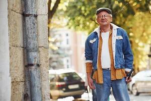 Stylish senior in fashionable clothes and in glasses have a walk in the city photo