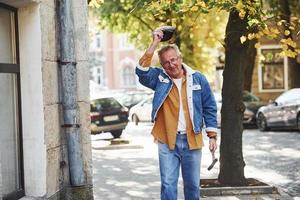 Stylish senior in fashionable clothes and in glasses have a walk in the city photo